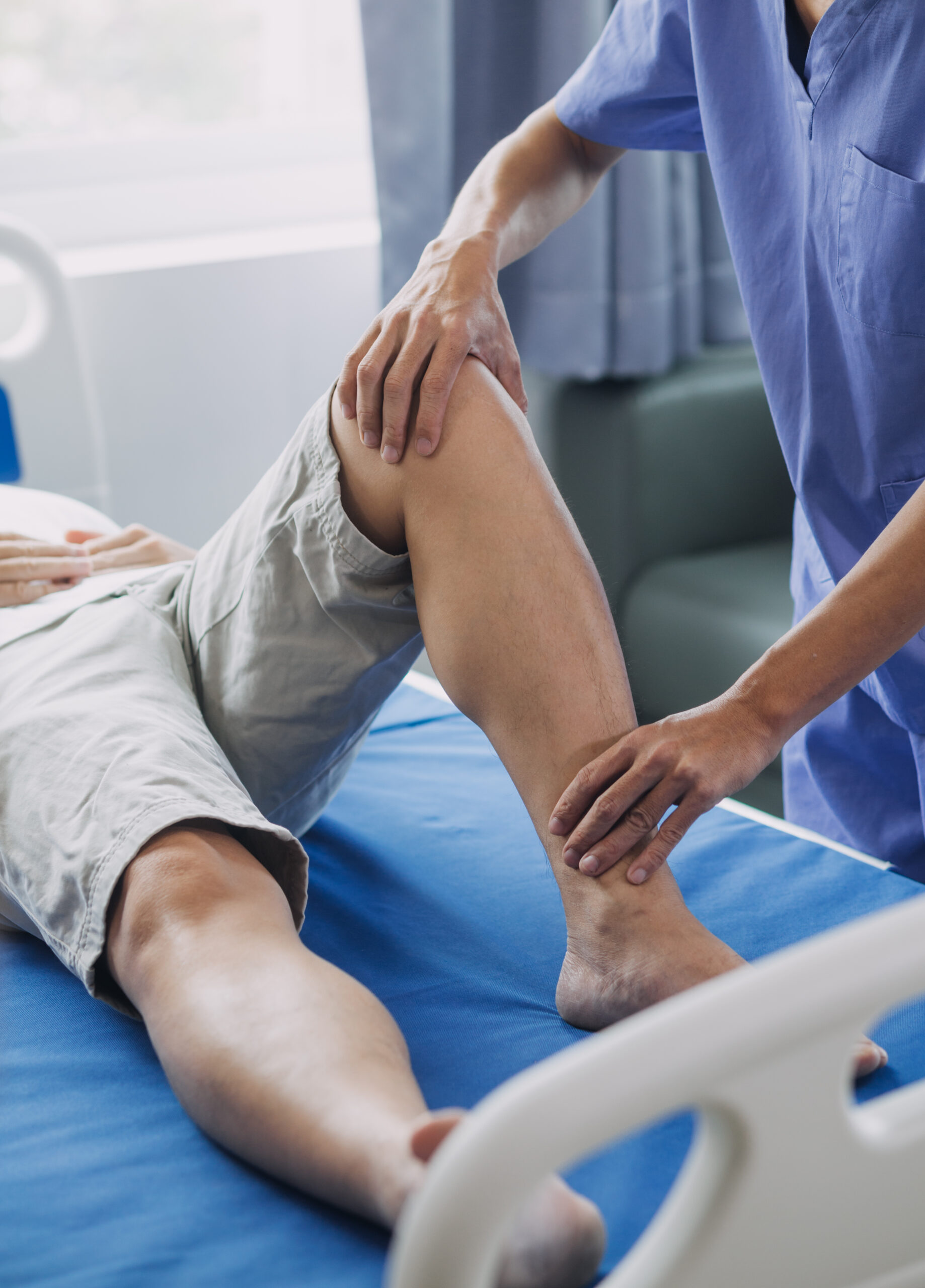 Doctor or Physiotherapist working examining treating injured knee